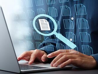 Magnifying glass documents person typing laptop